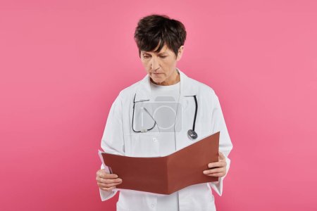 oncólogo de mediana edad, médico femenino mirando carpeta, concepto de conciencia de cáncer de mama, diagnóstico