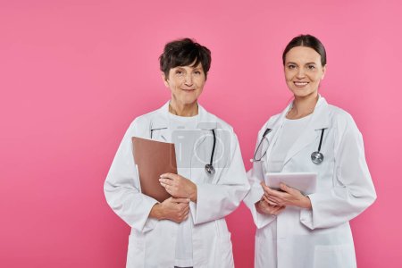 Foto de Oncólogos femeninos, médicos edad digital, tableta, carpeta, historial médico, conciencia sobre el cáncer de mama - Imagen libre de derechos