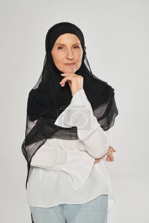 portrait of woman in hijab looking at camera and posing isolated on grey