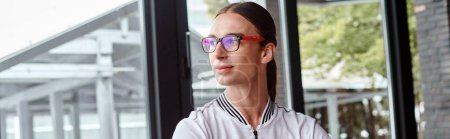 portrait of young smiling man in glasses with pony tail looking away outdoors, coworking, banner