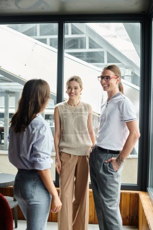 drei Smiley-Kollegen diskutieren etwas und lachen mit Fensterkulisse, Coworking-Konzept