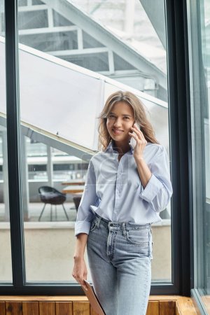 young attractive woman in business casual attire smiling and talking on phone, coworking concept