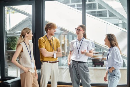 vier junge Mitarbeiter in schicken Casual Outfits lächeln aufrichtig über Arbeit, Coworking-Konzept