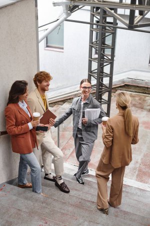 young happy colleagues standing outdoors talking and smiling at each other, coworking concept