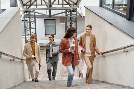cheerful coworkers in business casual outfits walking upstairs with coffee and paperwork, coworking