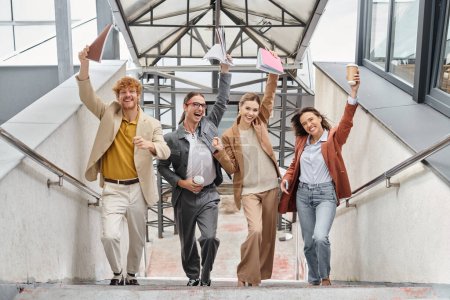 cheerful young teammates laughing and smiling with document raised in hands, coworking concept