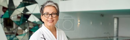 spa center and retreat concept, happy mature woman in glasses and robe looking at camera, banner