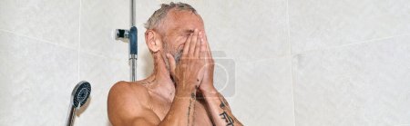 hombre de mediana edad y sin camisa con tatuajes que toman ducha y lavan la cara, higiene personal, pancarta