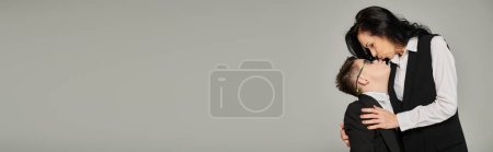 Téléchargez les photos : Femme d'affaires embrasser son fils avec le syndrome du duvet en uniforme scolaire sur gris, parent de soutien, bannière - en image libre de droit