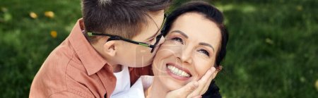Kind mit Down-Syndrom, Brille, küssende glückliche Mutter im Park, emotionale Verbindung, Banner