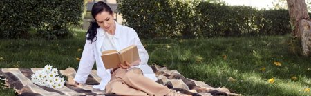 Téléchargez les photos : Femme d'âge moyen en tenue décontractée assis sur la couverture dans le parc et le livre de lecture, bannière - en image libre de droit