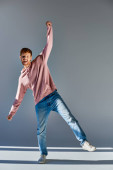 smiling red haired man in casual outfit standing on one leg with one hand raised looking at camera puzzle #674488714