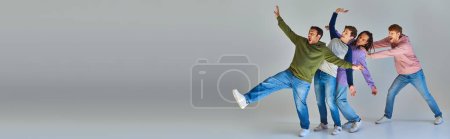 Photo for Playful friends in casual street attire having fun on grey backdrop, cultural diversity, banner - Royalty Free Image
