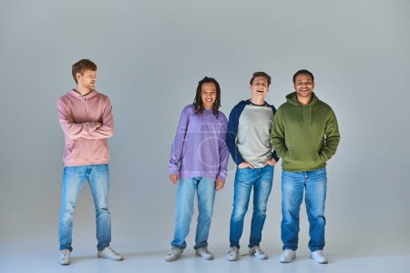 Foto de Jóvenes amigos con ropas cotidianas sonriendo sinceramente y posando sobre un fondo gris, diversidad cultural - Imagen libre de derechos