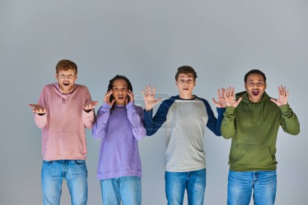 Téléchargez les photos : Quatre amis multiculturels choqués en tenue de rue colorée sur fond gris, diversité culturelle - en image libre de droit