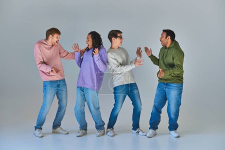 Foto de Cuatro hombres alegres sorprendidos en trajes urbanos brillantes mirándose, diversidad cultural - Imagen libre de derechos