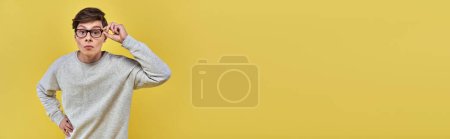 Photo for Slightly surprised man with glasses and casual attire touching glasses and looking at camera, banner - Royalty Free Image