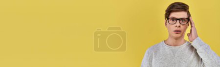 Photo for Astonished young man in casual outfit touching glasses and slightly opening his mouth, banner - Royalty Free Image