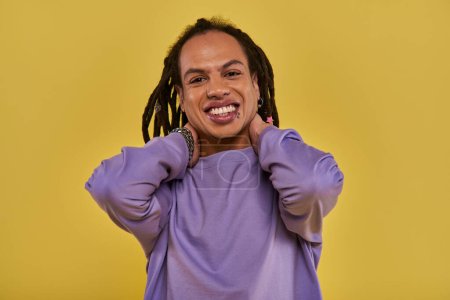 cheerful african american man with dreadlocks and pierced lip touching his neck smiling sincerely