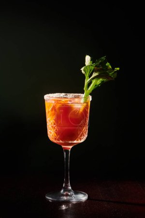 stunning bloody mary cocktail with celery stalk garnishing on black background, concept