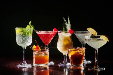 set of different sophisticated cocktails with fresh garnishing on black backdrop, concept