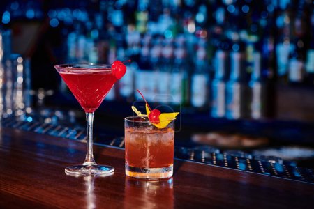 Téléchargez les photos : Cocktails exotiques sophistiqués décorés de cerises avec bar sur fond, concept - en image libre de droit