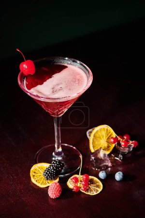 Téléchargez les photos : Cocktail cosmopolite élégant fruité avec glaçons fruités froids sur fond noir, concept - en image libre de droit