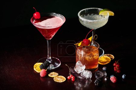 pikante und köstliche Cocktails mit Kirschen, Eis und Limette auf schwarzem Hintergrund, Konzept