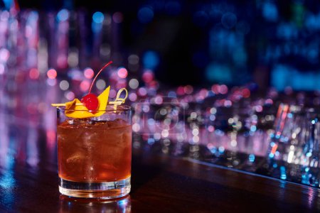 eisgekühltes Glas leckerer Negroni mit Cocktailkirsche mit Bar im Hintergrund, Konzept