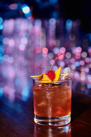 Photo for Sophisticated ice cold glass of negroni garnished with cherry with bar backdrop, concept - Royalty Free Image