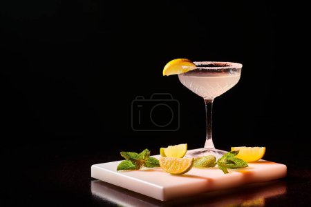 ice cold glass of delicious margarita garnished with slice of lime on bar counter, concept