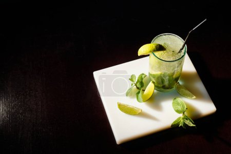 Volles Glas Mojito-Cocktail mit Eiswürfeln und Minze auf schwarzem Hintergrund, Konzept