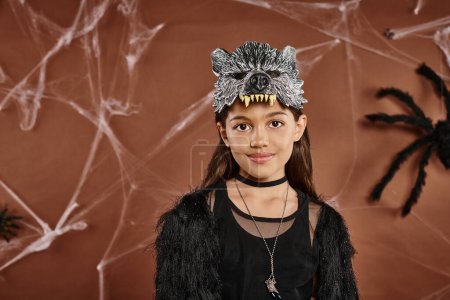 Foto de Linda chica en traje negro con máscara de lobo sobre fondo marrón, de cerca, concepto de Halloween - Imagen libre de derechos