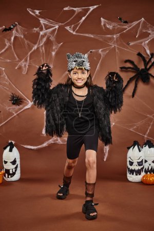 Smiley-Preteen-Mädchen erschrecken und posieren im Kunstpelzkostüm mit Wolfsmaske, Halloween-Konzept