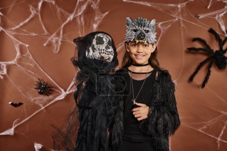Nahaufnahme fröhliches vorpubertierendes Mädchen in Wolfsmaske zeigt Halloween-Spielzeug, Halloween-Konzept
