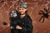 close up smiling preteen girl holds spooky toy on brown backdrop, Halloween concept magic mug #676677246