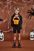 happy girl holding bucket of sweets in wolf mask and black attire, Halloween concept magic mug #676677324