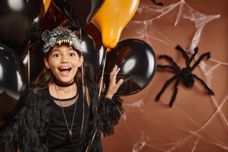 cerrar feliz niña preadolescente con globos con telón de fondo de tela de araña marrón, concepto de Halloween