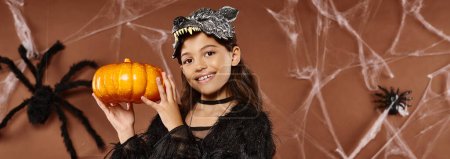 preteen girl holds pumpkin in her hands aside wearing wolf mask, Halloween concept, banner