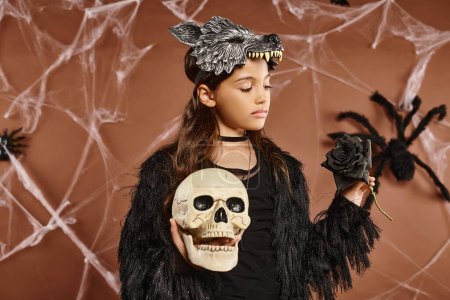 Nahaufnahme Frühchen hält Totenkopf und schwarze Rose in den Händen mit Wolfsmaske, Halloween-Konzept