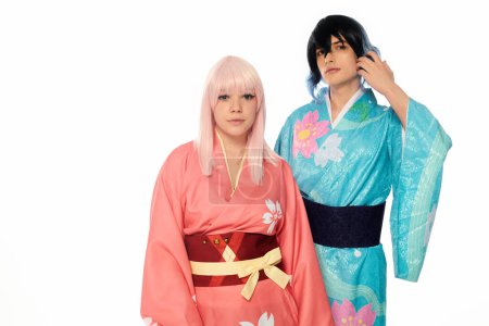 jeune couple cosplay en kimonos colorés et perruques regardant la caméra sur blanc, bannière horizontale