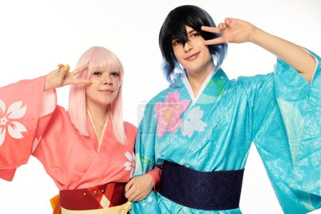 Lächelndes Paar Cosplayer in bunten Kimonos mit Siegeszeichen auf weißem Anime-Konzept