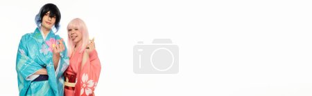 Photo for Playful anime woman sticking out tongue and showing mini hearts with man in kimono on white, banner - Royalty Free Image