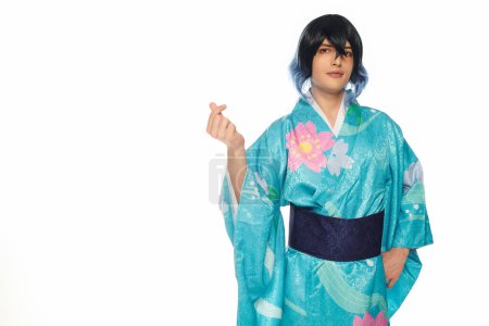 young man in extravagant wig and kimono showing mini heart gesture with fingers on white, cosplayer