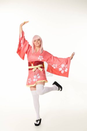 fröhliche Frau im Anime-Stil in lebendiger traditioneller Kleidung posiert auf weißer, japanischer Cosplay-Kultur