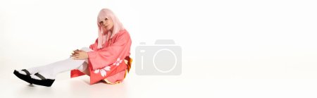 blonde anime style woman in pink kimono sitting and looking at camera on white, horizontal banner