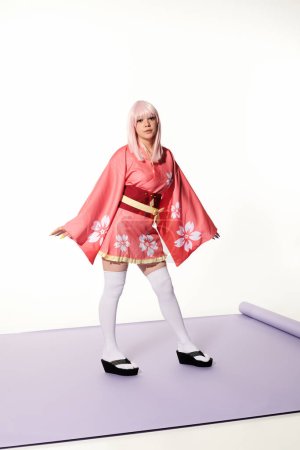 japanese cosplay subculture, blonde woman in kimono and wig on purple carper and white backdrop