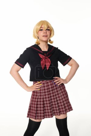 confident woman in yellow blonde wig and school uniform with hands on hips on white, cosplay concept