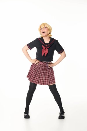 cosplay concept, woman in yellow blonde wig and school uniform posing with hands on hips on white