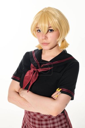 portrait of young woman in yellow blonde wig and school uniform looking at camera on white, cosplay